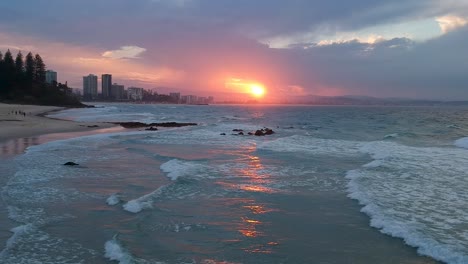 drone shot going sideways over ocean waves with redish beach sunset in australia coolangatta