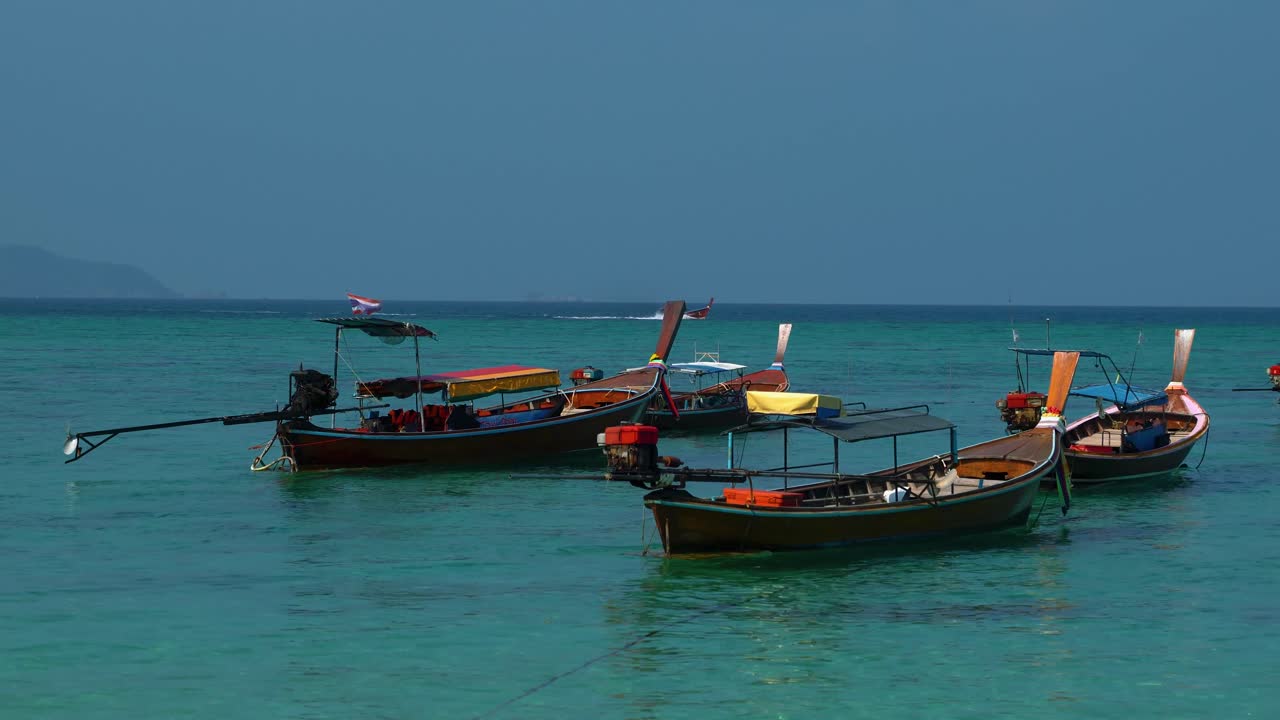 Traditional and iconic Thai longtail boats on an empty sandy beach on the remote island Koh Lipe in Thailand, close to the Malaysian border. The water is turquoise and clear like in paradise.