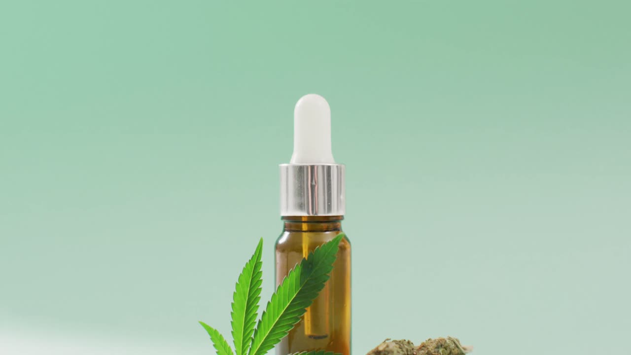 video di foglie e germogli di marijuana e bottiglia di estratto di cbd su sfondo blu