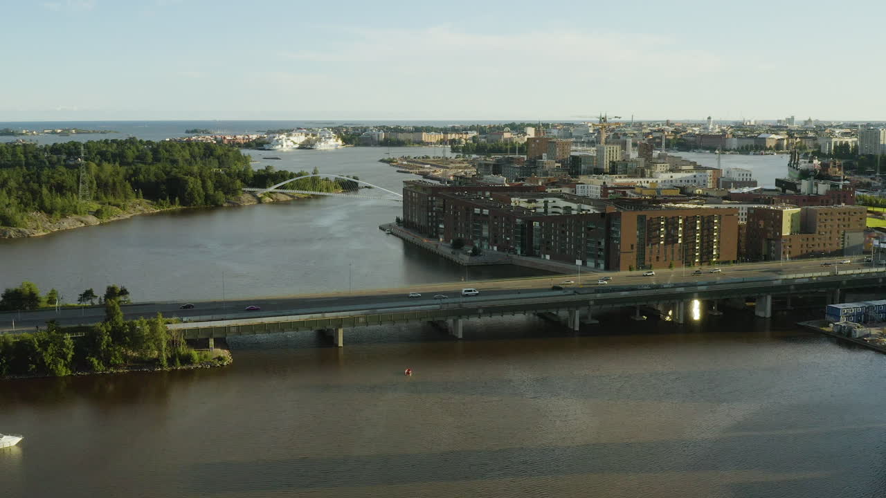 Veduta aerea del traffico su un ponte, sulla strada 170, la Itäväylä, nel quartiere di Kalasatama, durante l'ora d'oro, a Helsinki, Finlandia - tracking, panoramica, ripresa con drone