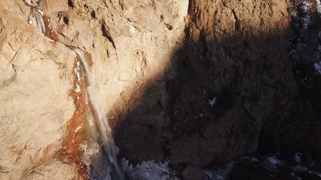 breathtaking view of a cascade waterfall in a cold winter. frozen icicle around the cliff and roaring water fall from a high rocky mountain.