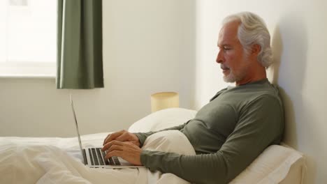senior man using laptop on bed in bedroom 4k