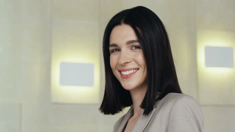 close-up view young caucasian businesswoman in formal clothes on a podium looking at the camera and smiling in a meeting room