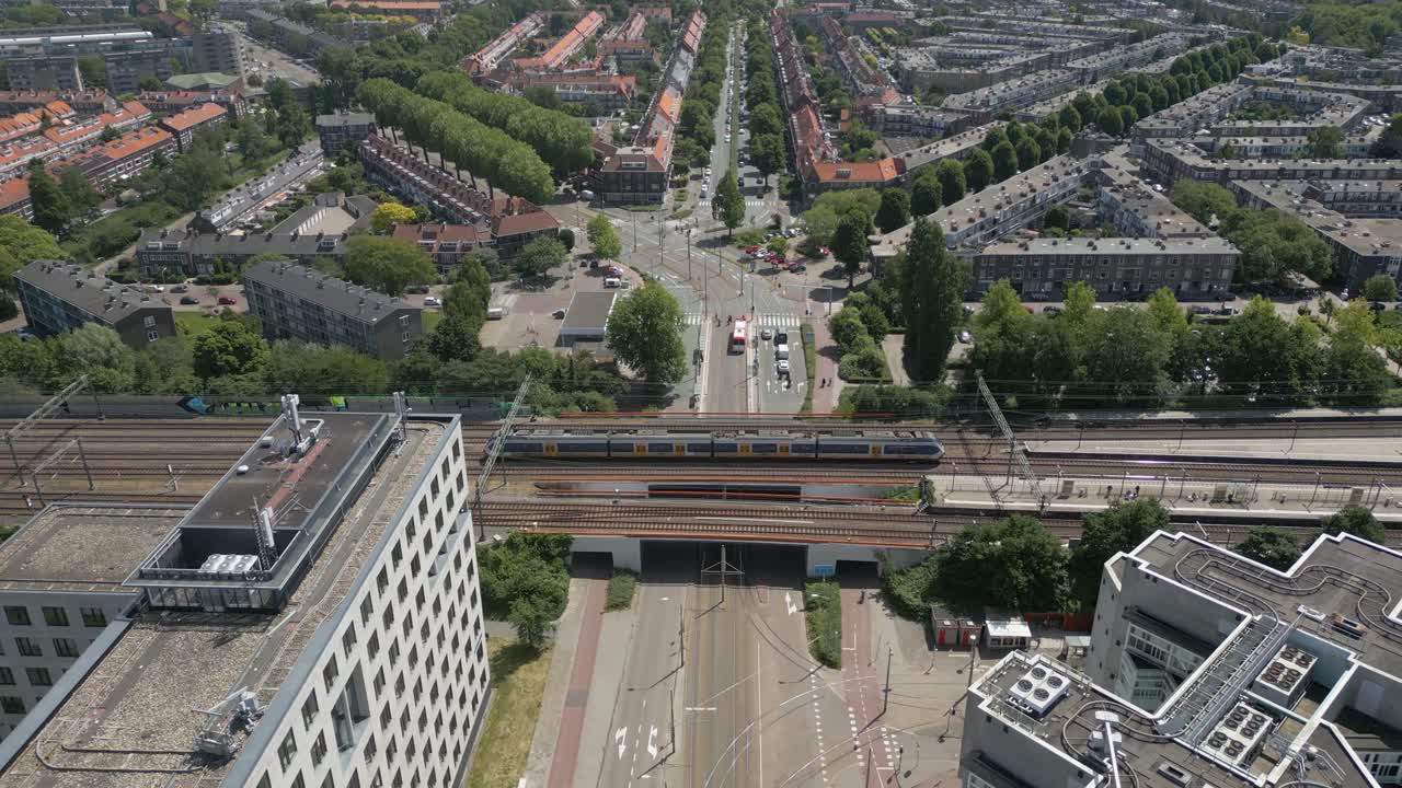A top-down view of a modern urban area with trams, roadways, and residential housing in The Hague.