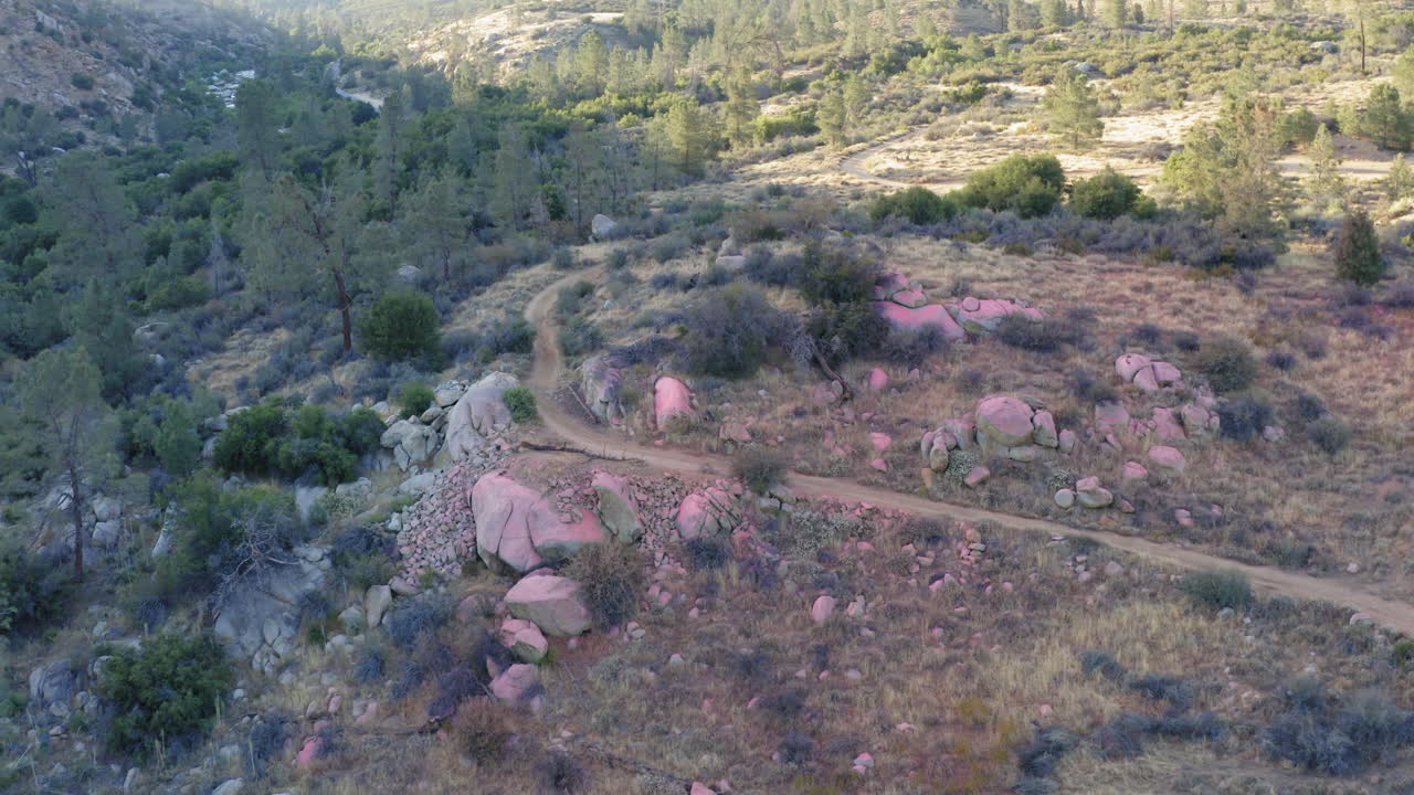 Mountain valley covered in red fire retardant dropped over forest fire, aerial