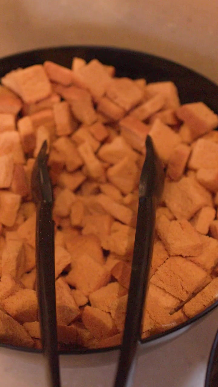 Nahaufnahme-Kameraschwenk über schwarze Schalen mit runden Crackern und knusprigen Croutons an einer Buffetstation.