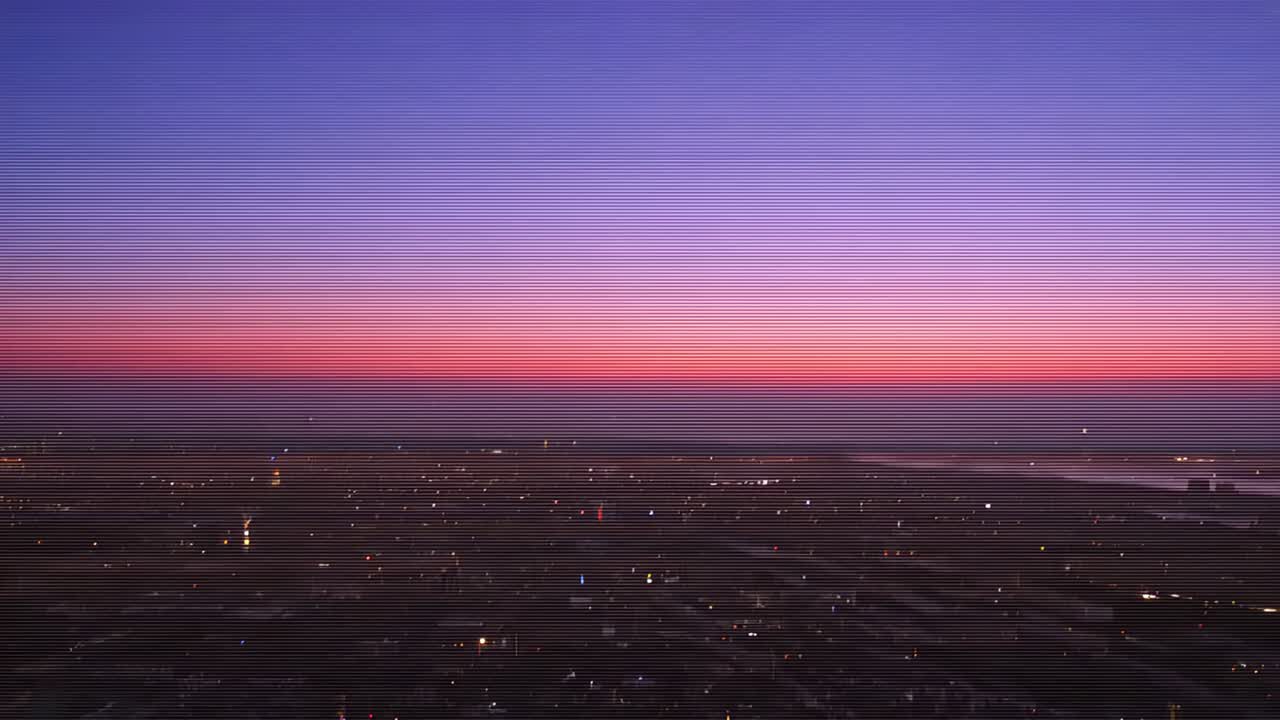 Shifting pink-blue horizon and city lights lighting coastal harbor at twilight showing beacon piers