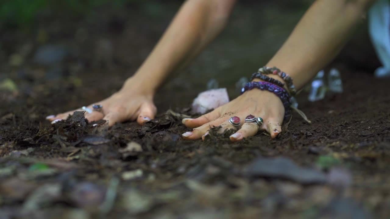 Close-up view of a person's hands rubbing the ground and meditating with a crystal stone on the riverbank in the Salto Encantado park located in Misiones, Argentina