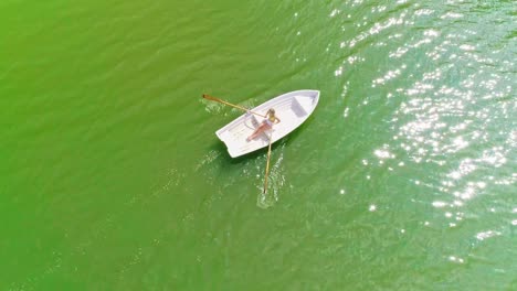 Vista-Aérea-De-Una-Mujer-Joven,-Bella-Y-Sexy-Con-Bikini,-Remando-Sola-En-Un-Bote-Blanco-En-El-Mar