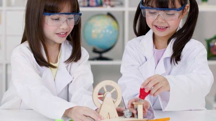 To folkeskoleelever bærer sikkerhedsbriller, mens de samler en trægenerator-model i et skolelaboratorium.