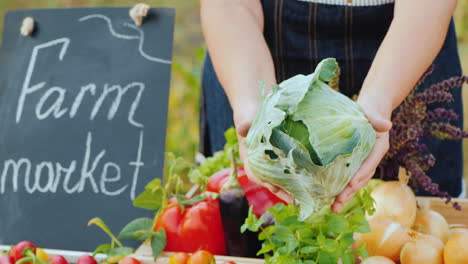 Las-Manos-Del-Agricultor-Con-Una-Cabeza-De-Repollo-En-El-Mostrador-De-Venta-De-Verduras-En-El-Mercado-De-Agricultores