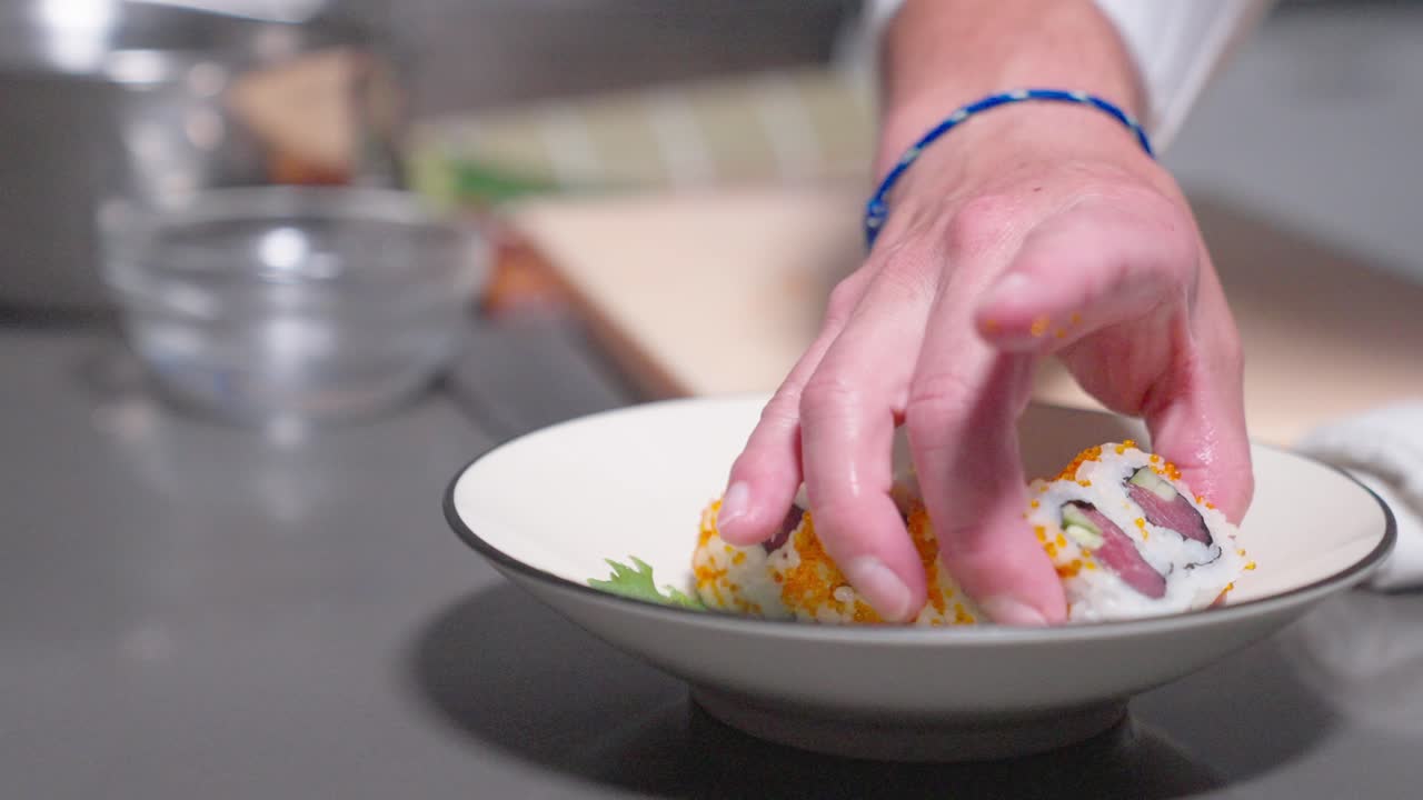 A roaming shot captures a sushi chef carefully placing sushi rolls into a bowl, showcasing the art of sushi presentation. Ideal for food, culinary, and sushi-making content.