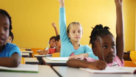 school kids raising hand in classroom