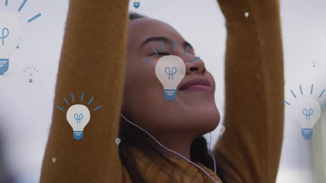 animation of lightbulbs over happy biracial woman with earphones