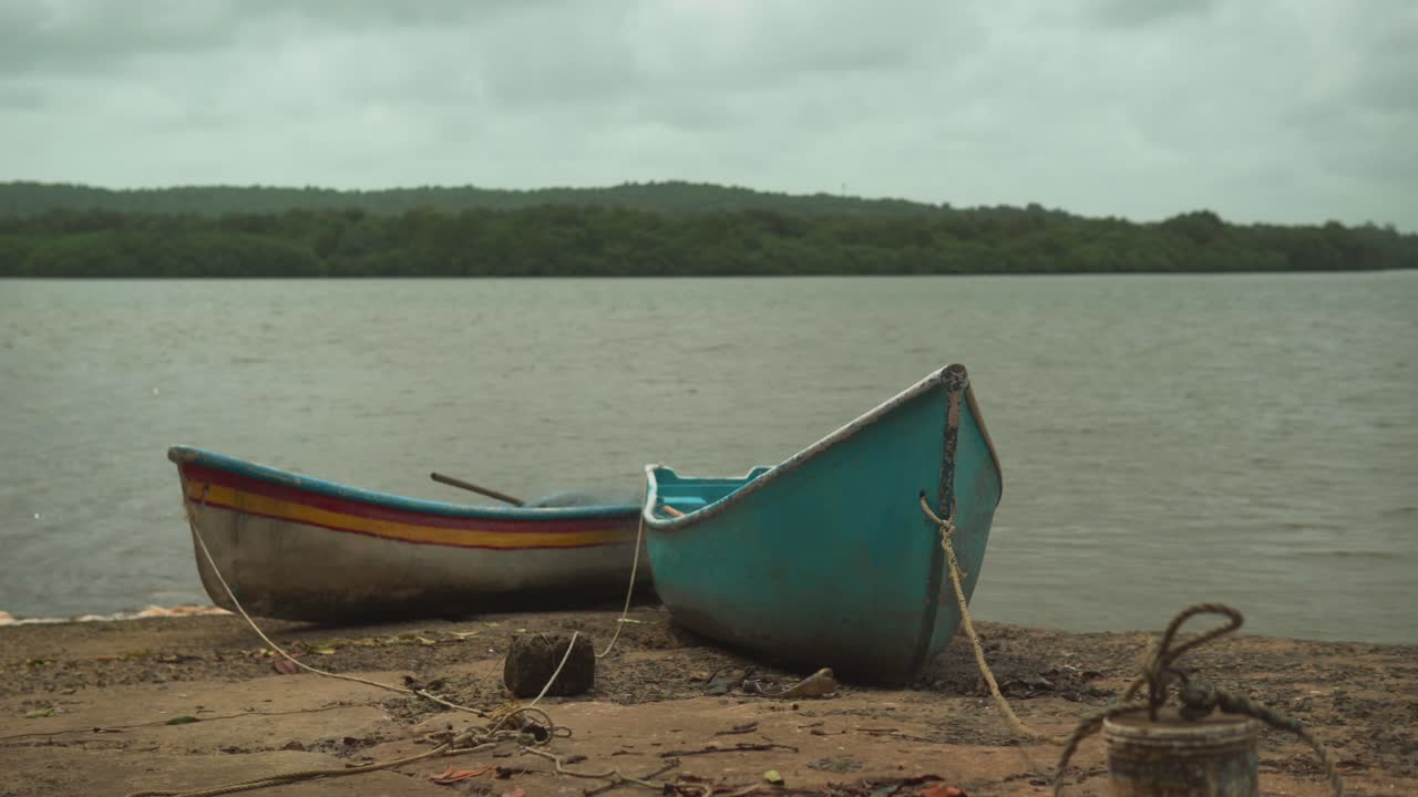 barcos de pesca de madera atados con una cuerda yacen en la arena en la playa contra el telón de fondo de las palmeras en el bosque de goa, india