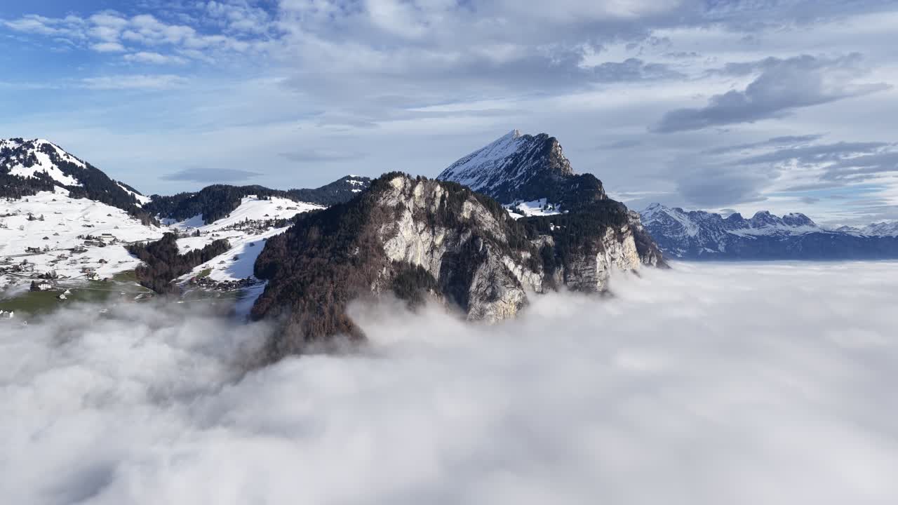 Islands of rock and snow. The Churfirsten mountains in Switzerland dramatically emerge from a dense, white ocean of cloud inversion. A spectacular view over the Walensee Amden region