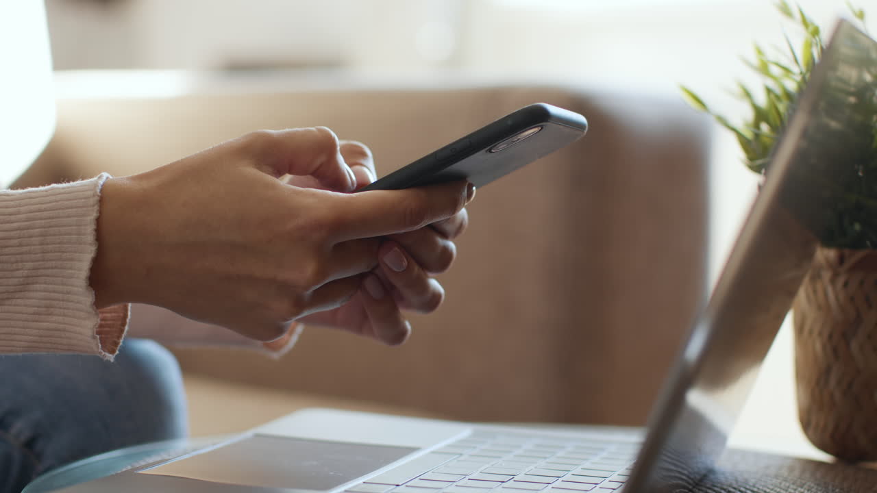 mujer usando teléfono inteligente y portátil en casa