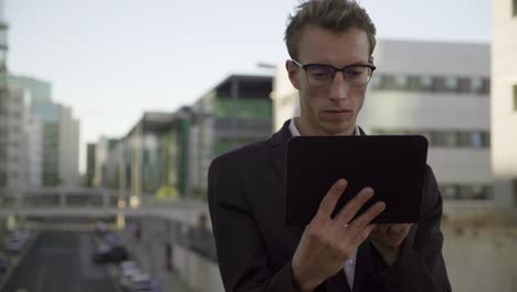 Good looking man standing outside, working on tablet