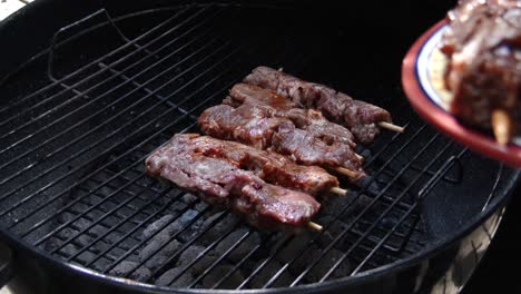 placing shish kebabs onto a grill during a barbecue, close up