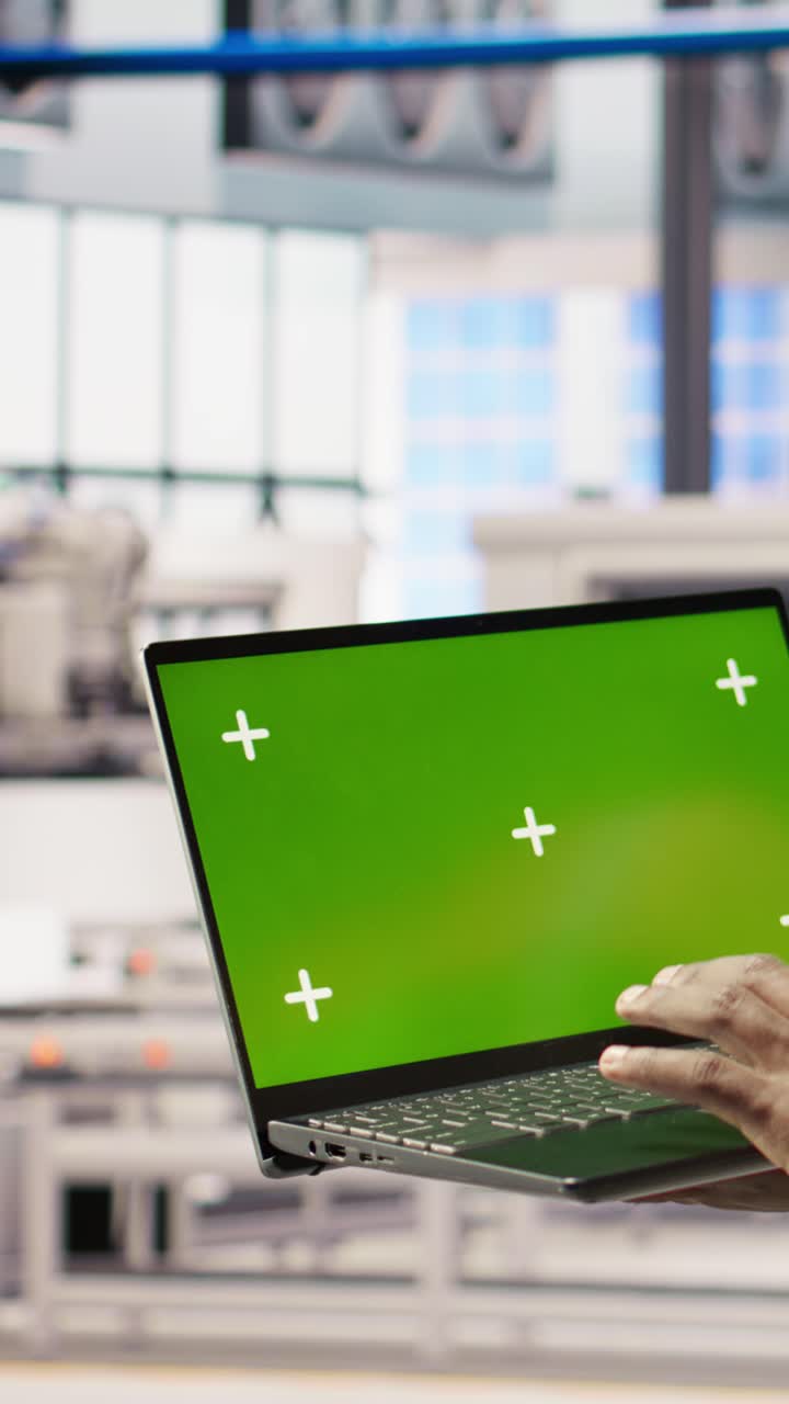 Vertical video Smart factory mechanic testing automated systems using isolated screen laptop