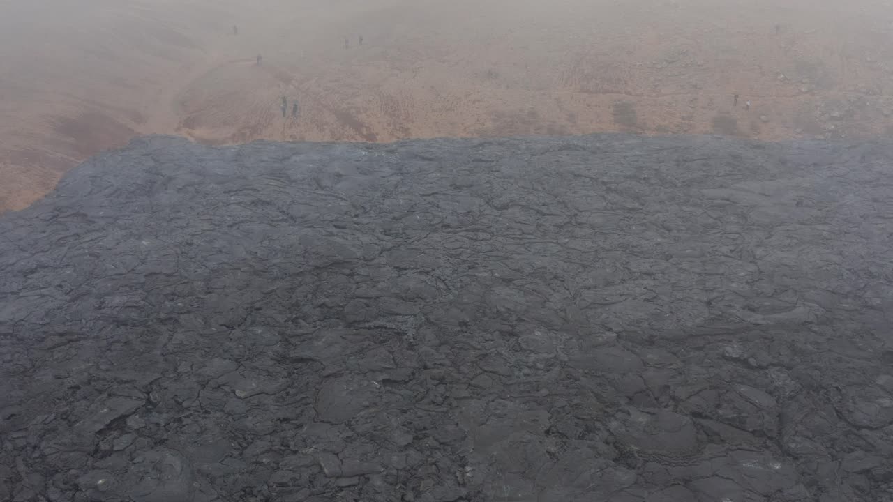 Rain clouds above black basalt field in Iceland valley, aerial