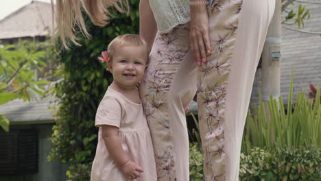 caucasian baby girl holding mothers leg