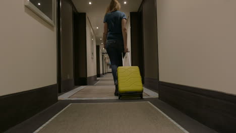 woman with suitcase walking in hotel corridor