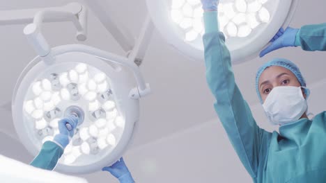 low angle of biracial female surgical assistant preparing lights in operating theatre, copy space