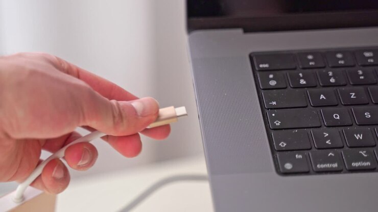 A hand comes into the close-up scene and plugs in a USB-C adaptor for other peripherals