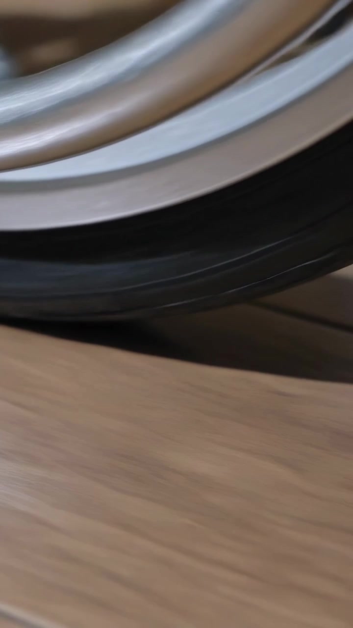 Vertical video: Shifting metal rim, rubber ring rotating from camera move on wood table with shadow