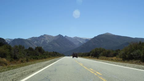 Jeep-Driving-By-on-Secluded-Road,-Mountain-Background-Rear-View-Static