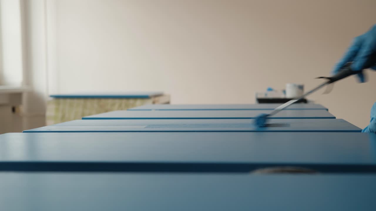 Female painting cabinet doors with blue paint and roller