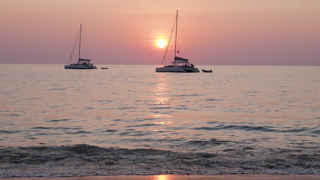 해변에서 파스텔 색상의 일몰 앞에 있는 범선 - 매우 느린 동작이 위로 기울어짐