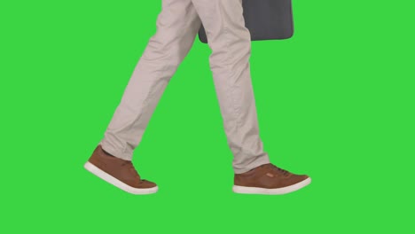 mans feet is walking in jeans and sneakers on a green screen, chroma key