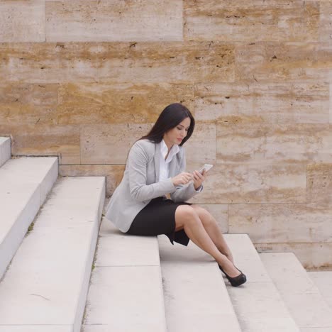 Mujer-De-Negocios-Bonita-Sentada-En-Pasos-Usando-El-Teléfono