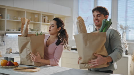 husband bringing products bags to wife standing kitchen close up. happy couple