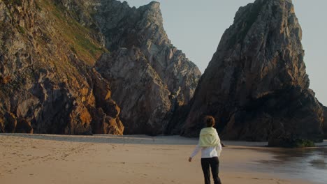 woman walking on a beach with rocky coastline