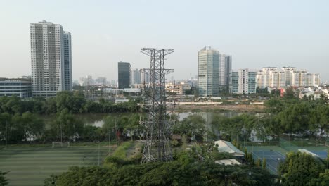 drone shot flying upward revealing ho chi minh city skyline seen from nha be over rach dia river over a giant transmission tower