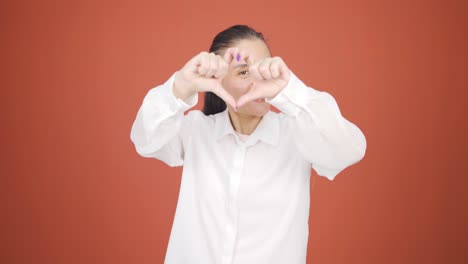 woman making heart sign at camera.