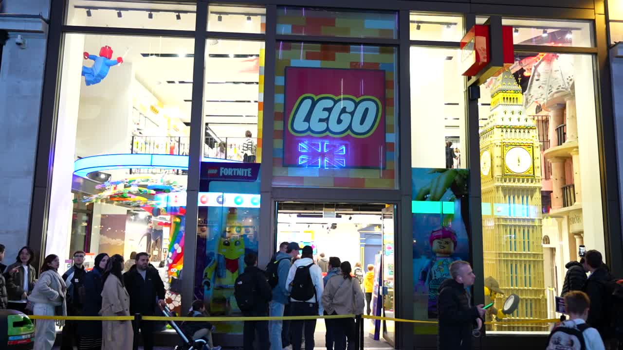 Tourists queue outside the colorful Lego Store in Leicester Square, London, during nighttime