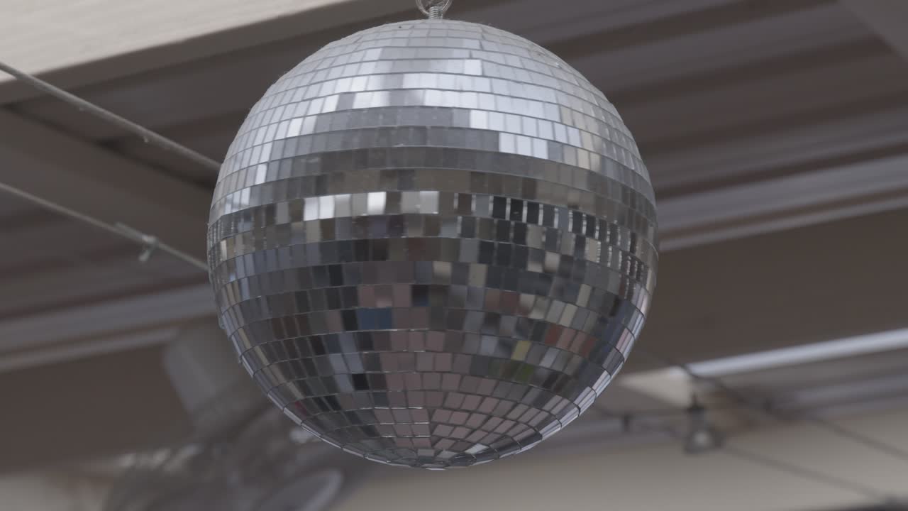 Una bola de discoteca clásica con efecto espejo cuelga del techo de un local. Este vídeo LOG sin editar es un lienzo en blanco, perfecto para crear una fiesta vibrante o una escena tranquila y nostálgica.