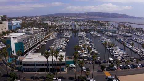 Low-aerial-dolly-shot-of-the-King-Harbor-Marina-looking-towards-the-Palos-Verdes-peninsula-in-Redondo-Beach,-California