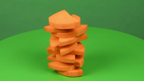 sliced butternut squash (cucurbita moschata, butternut pumpkin or guitar gramma) isolated on green. side view. loop motion. rotation 360