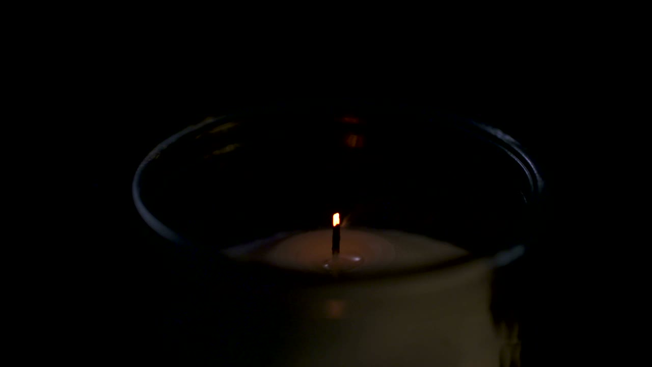 Filmato macro in slow motion di una candela bianca su sfondo scuro