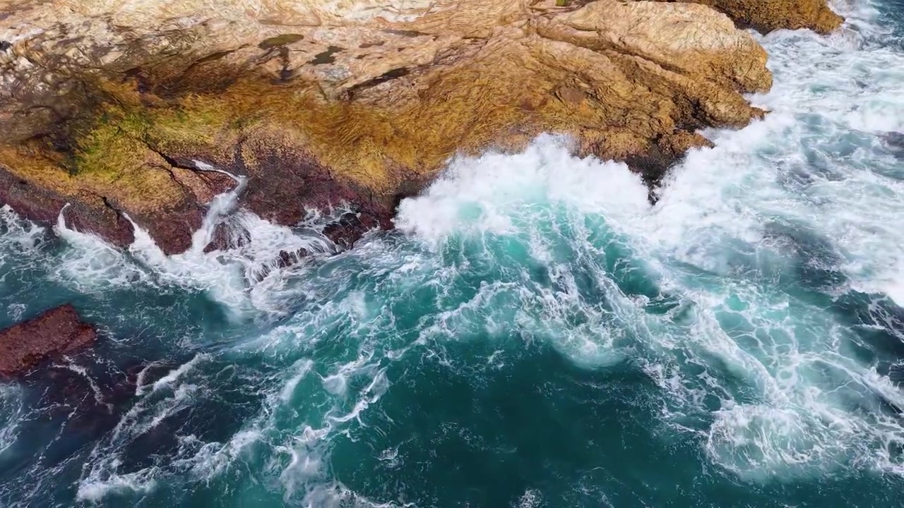 Superficie ondulata dell'acqua dell'oceano contro una costa rocciosa.