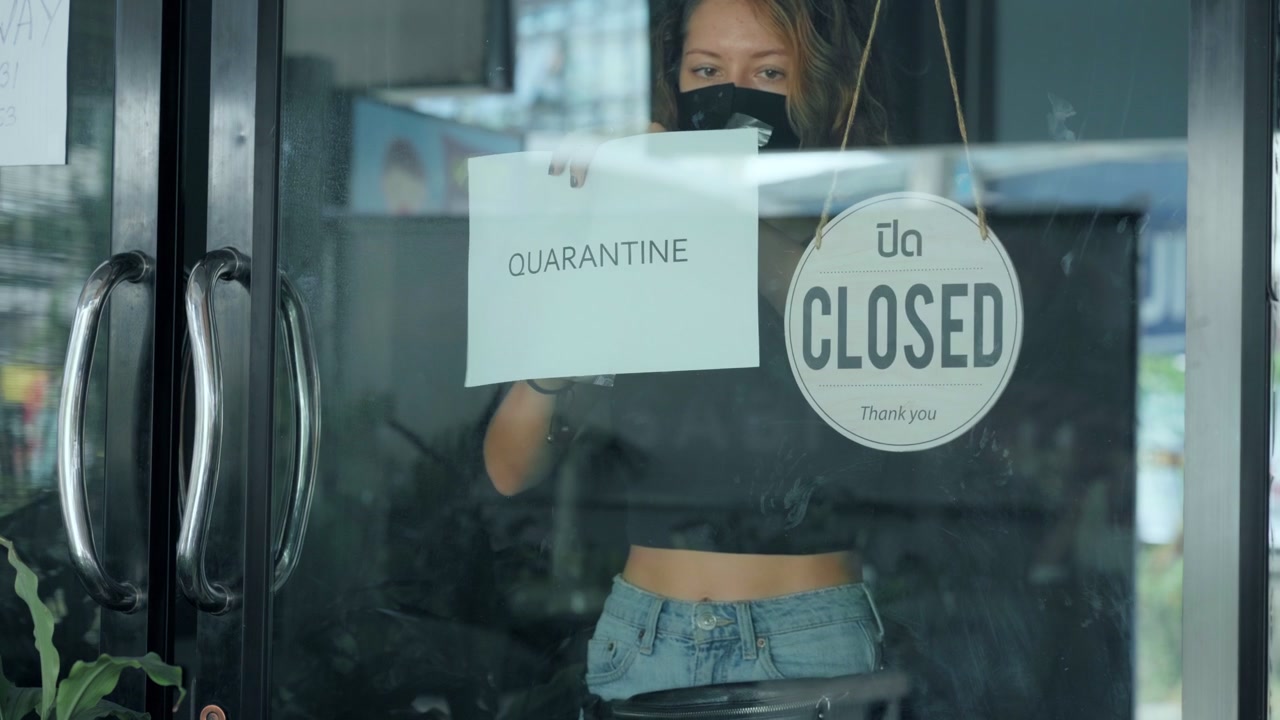 Woman Placing Quarantine Sign on Glass Door of Closed Shop