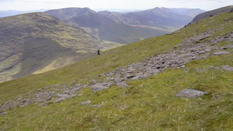 Schwenk-Einer-Person,-Die-Auf-Dem-Kamm-Eines-Hohen-Berges-Mit-Malerischen-Landschaften-In-Irland-Bei-Mcgillycuddy-Reeks-In-4k-Läuft