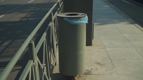 a concrete trash can with blue plastic situated on the side walk in cluj-napoca county. -medium shot