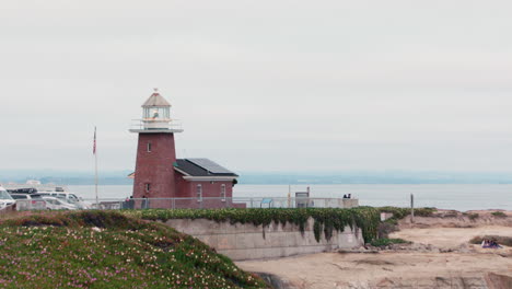 Santa-Cruz-Lighthouse-with-American-Flag,-Ocean,-and-Coastline