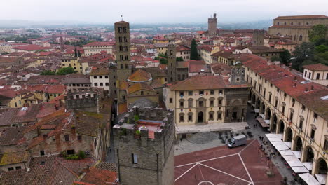 piazza grande with medieval church and buildings in tuscany, italy - aerial drone shot